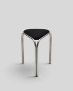 ESTYNE Studio Atelier Stool with a polished stainless steel frame and a soft black velvet triangular seat.