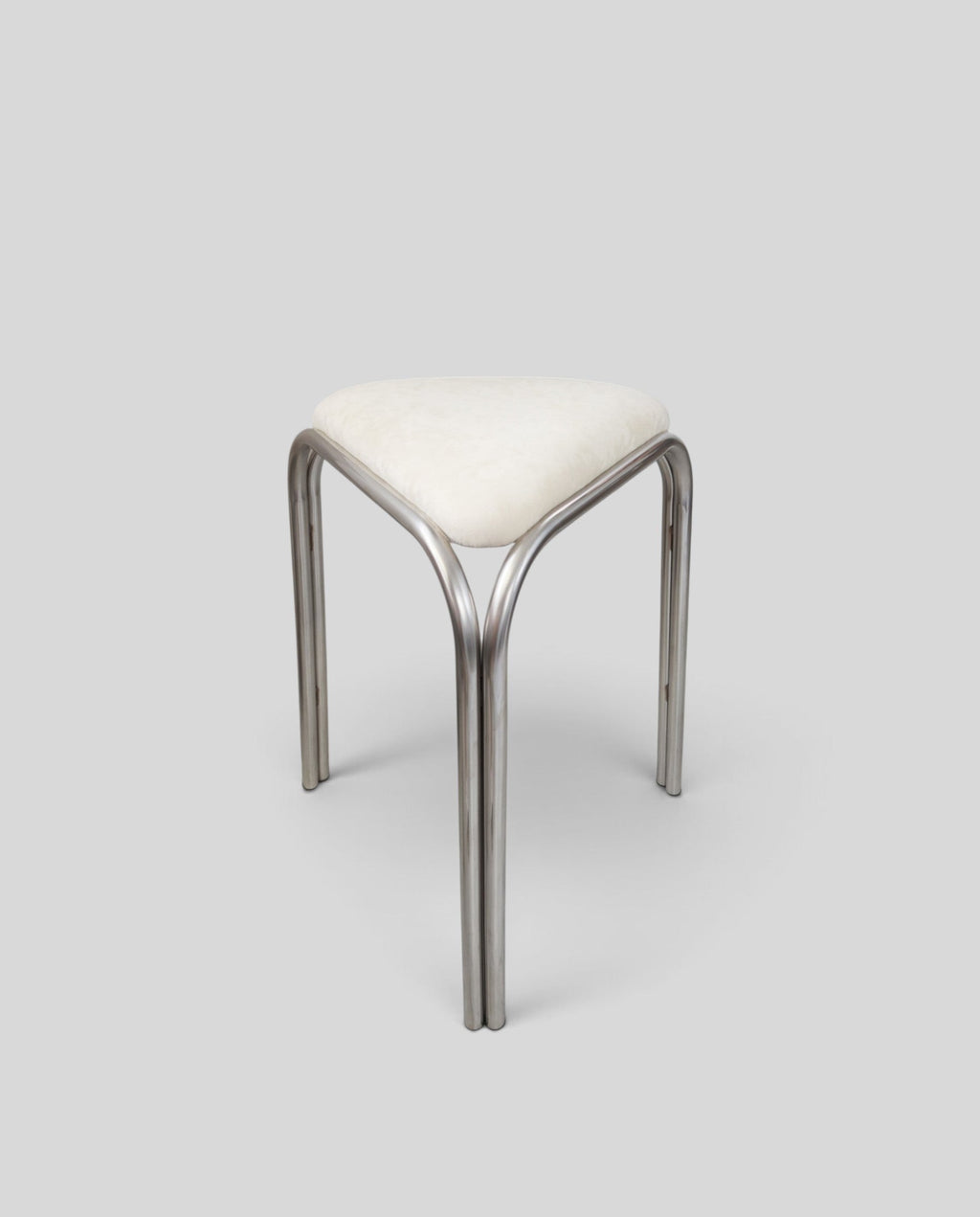ESTYNE Studio Atelier Stool with a polished stainless steel frame and a soft cream velvet triangular seat.