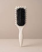 Skin Meets Restore Scalp Brush with a speckled cream handle and black flexible nylon bristles for gentle detangling.