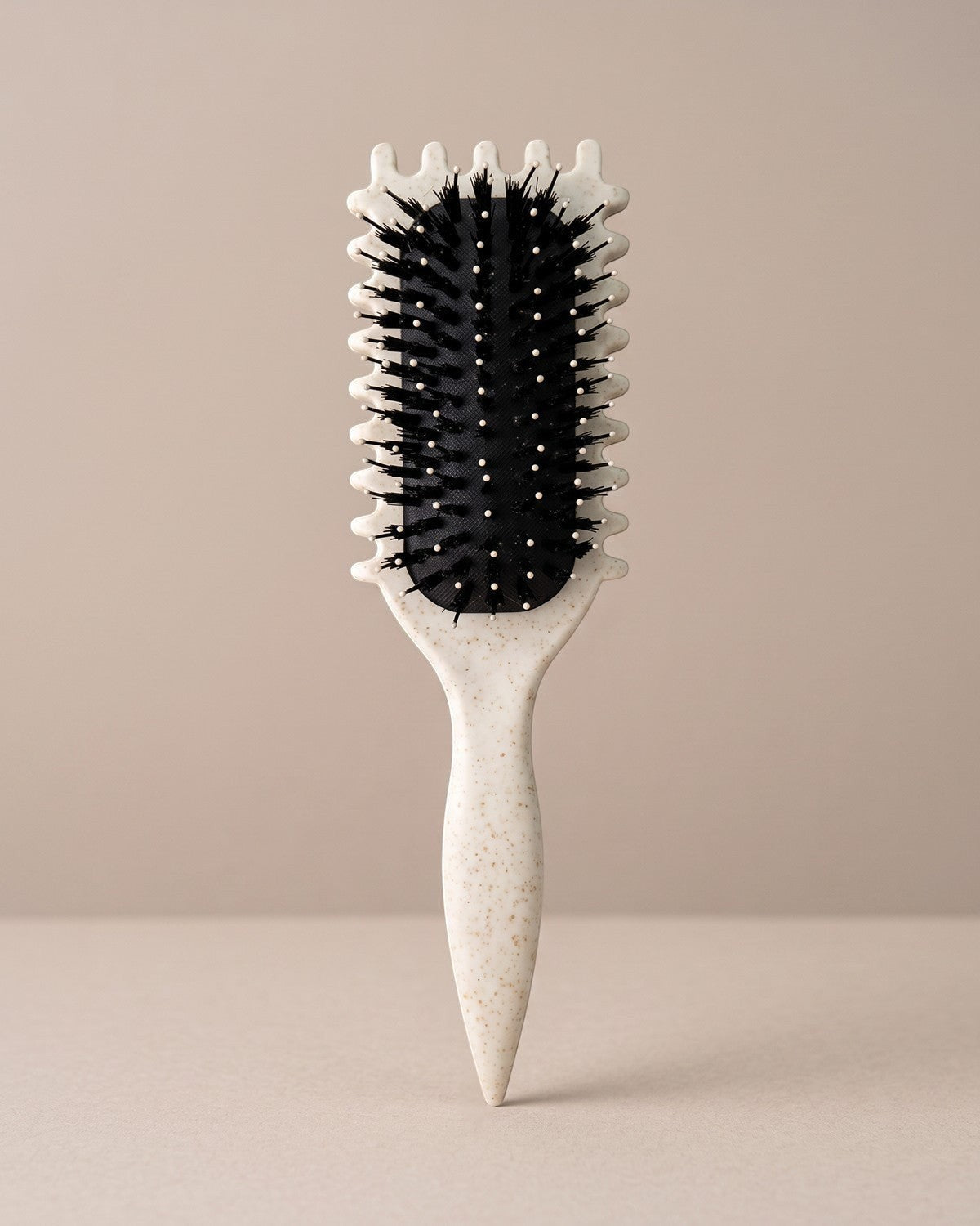 Skin Meets Restore Scalp Brush with a speckled cream handle and black flexible nylon bristles for gentle detangling.